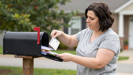 mujer examinando su correo junto a un buzon generated with Z-Image